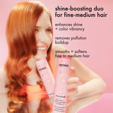 Woman with red hair holding two pink hair care products against a pink background