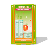 A product image of Amika's 'Play Your Strength' strength repair routine set. The box is predominantly green with a retro-inspired design. The front of the box displays the three full-size products included: The Kure Bond Repair Shampoo, The Kure Bond Repair Conditioner, and The Kure Intense Bond Repair Mask. The packaging features bright, vibrant colors and a small illustration of an orange with a leaf. The text on the box reads 'Play Your Strength' in a pink and white banner, with additional details about 