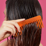 image of a model combining through their hair with an orange comb. the hair appears shiny after applying the wizard silicone-free. 