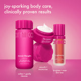 three bright pink amika body products are arranged on a pink surface, including a body wash, open cream jar, and serum. text reads “joy-sparking body care, clinically proven results,” with routine steps labeled beneath each product.