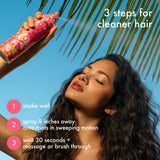 Woman using a hair care product with text on steps for cleaner hair against a blue sky and palm tree background.