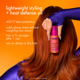 Person with red hair holding a bottle of Amika Superfruit Oil against an orange background