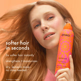 Woman holding an orange bottle of amika hair mask with text about hair benefits on a peach background