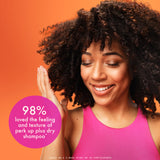 Woman with curly hair wearing a pink tank top against an orange background, with a text overlay about shampoo.