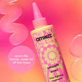 Amika smooth over frizz-fighting treatment bottle with pink and yellow design on a colorful background