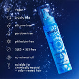 Blue spray bottle with 'amika' branding on a dark blue background with product benefits listed.