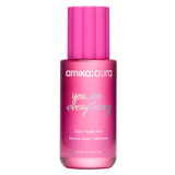 A bottle of amika:aura 'you are everything' hair and body mist in a translucent pink bottle with a bright pink cap, shown on a solid white background.