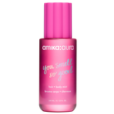 A pink bottle of amika:aura 'you smell so good' hair and body mist, featuring a matching pink ribbed cap, on a solid white background.