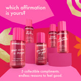 Five amika:aura hair and body mist bottles in bright pink packaging are arranged on pink pedestals against a vivid pink graphic background with gold abstract shapes and white text reading 'which affirmation is yours?' and '5 collectible compliments. endless reasons to feel good.
