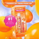 A promotional image for Amika's 'Perk Up Power-Up' dry shampoo duo set. The image shows the orange and pink packaging box against a vibrant background with floating orange balloons. The text at the top reads 'Power Up Your Perk Up,' and a pink graphic highlights '#1 prestige dry shampoo SKU in the U.S.